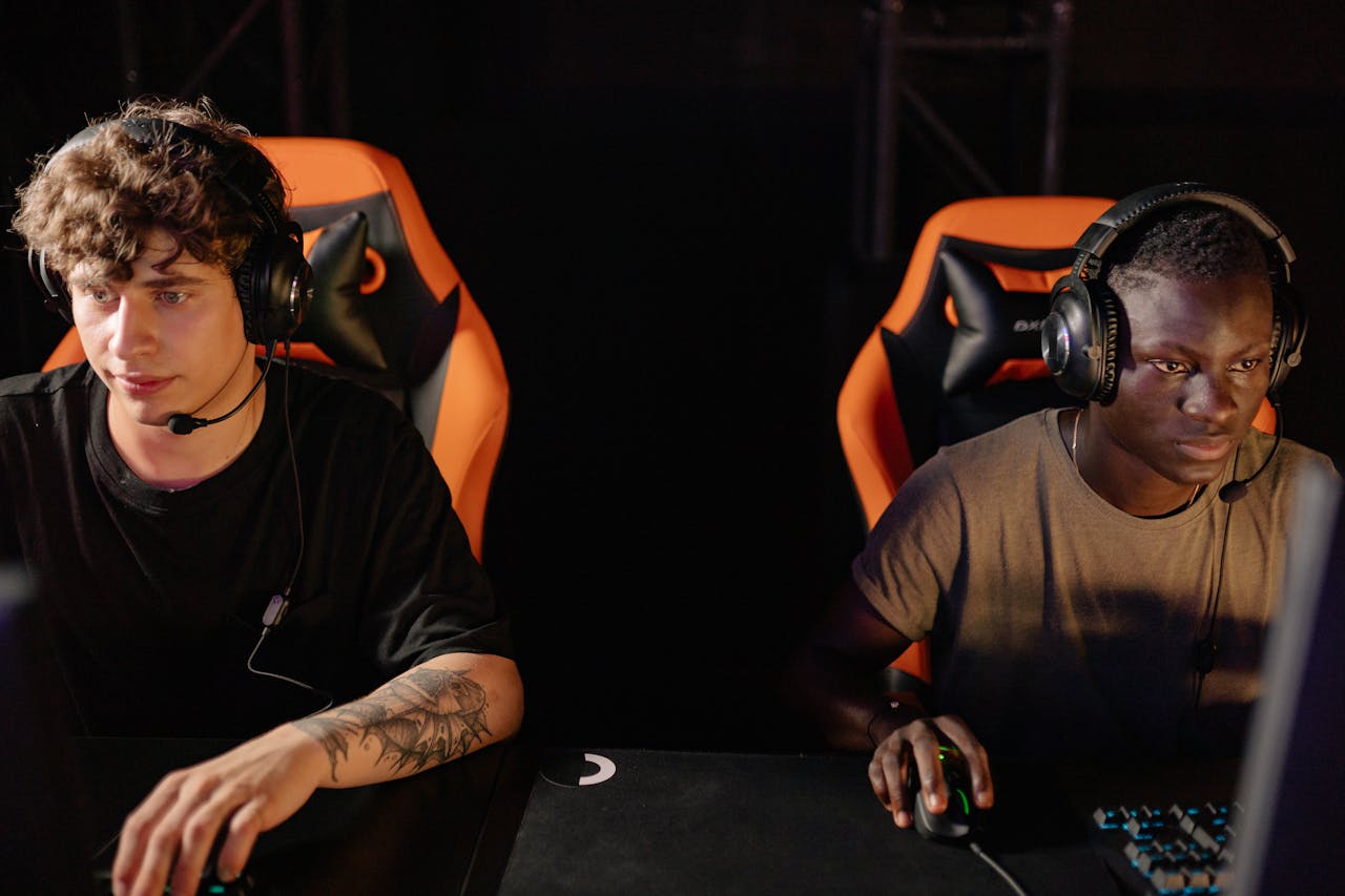 Friends laughing while playing video games together on a sofa.