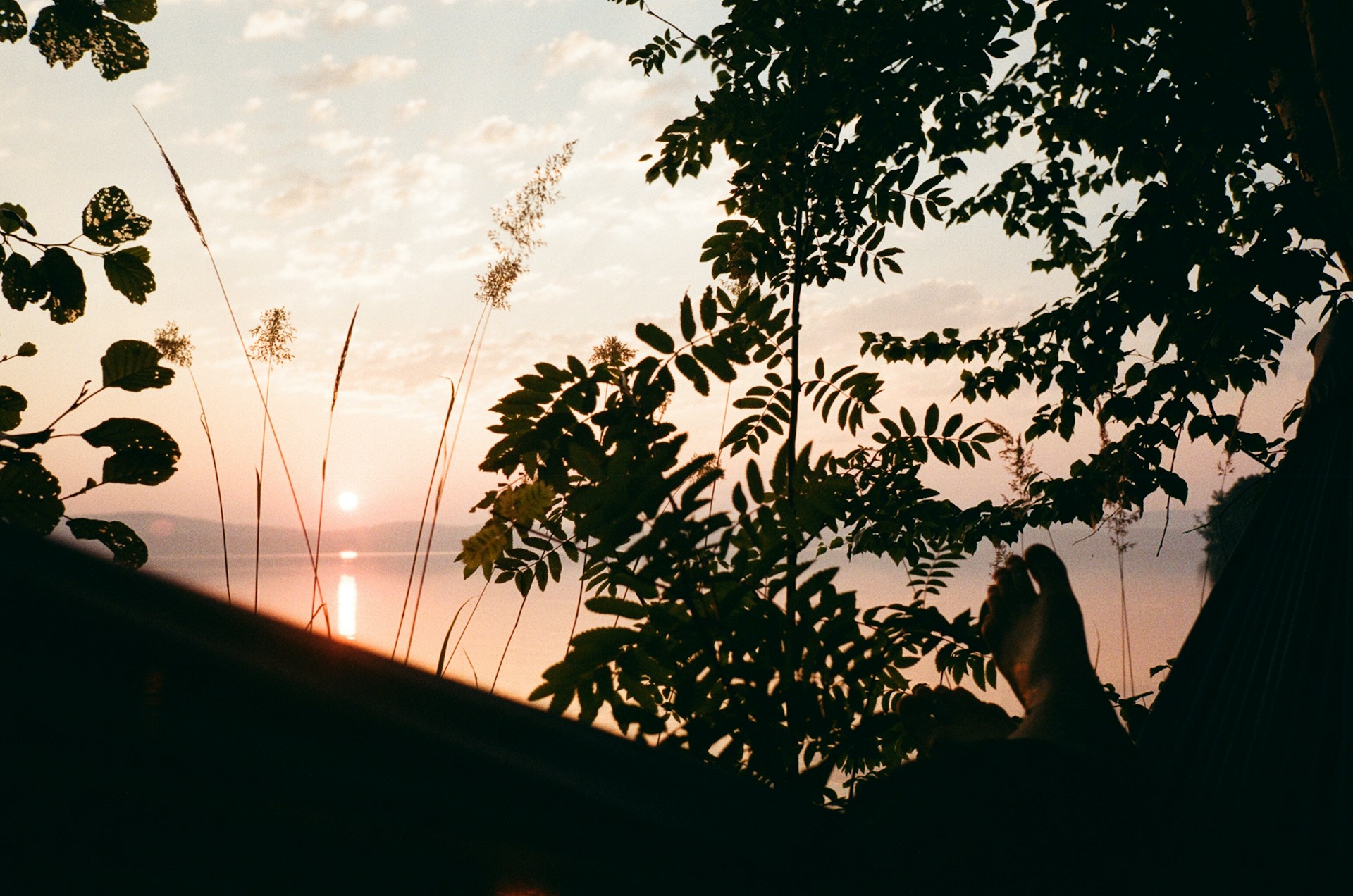 A person relaxing in a hammock and watching the sunset.